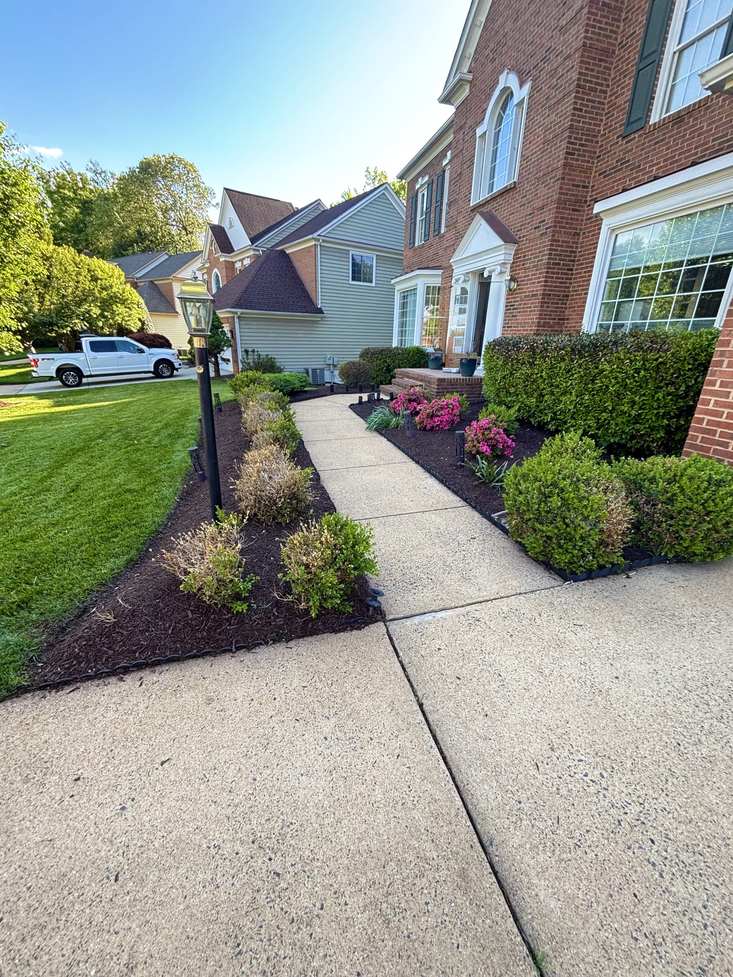 Fresh front walkway landscaping with dark mulch and green lawn